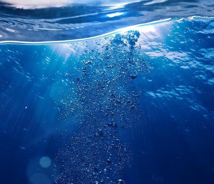 Clear blue water with sprinkles of water bubbles shown through sunlight